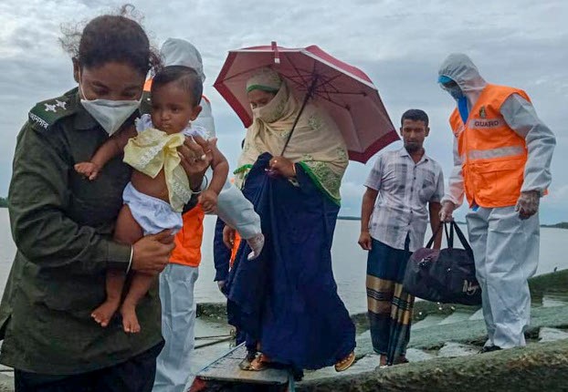 সাতক্ষীরায় ঘূর্ণিঝড় আম্পানের কারণে একটি পরিবারকে আশ্রয় কেন্দ্রে সরিয়ে নিতে সহায়তা করছেন একজন আনসার সদস্য। ২০ মে ২০২০। 
