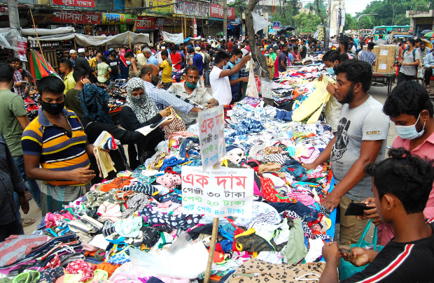 করোনাভাইরাস সংক্রমণের ভয় এড়িয়ে ঢাকার ফুটপাতে শেষ মুহূর্তের ঈদের বাজার করছেন ক্রেতারা। ৩০ জুলাই ২০২০। 