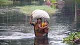 বন্যার পানিতে ঘরবাড়ি ভেঙে পড়ায় সন্তান নিয়ে আশ্রয়ের সন্ধানে ছুটছেন একজন মা।