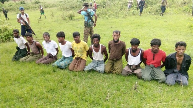 মিয়ানমারের রাখাইন রাজ্যের ইন দিন গ্রামে দেশটির সেনাসদস্যরা কয়েকজন রোহিঙ্গাকে পেছনে হাত বেঁধে হাঁটু মুড়িয়ে একটি মাঠে বসিয়ে রেখেছেন। ২ সেপ্টেম্বর ২০১৭। [রয়টার্স]