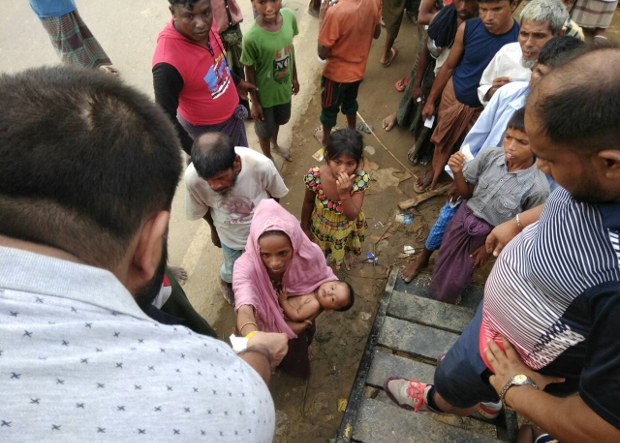 উখিয়ার পালংখালী এলাকায় সন্তান কোলে ত্রাণ নিচ্ছেন একজন রোহিঙ্গা নারী উখিয়ার পালংখালী এলাকায় সন্তান কোলে ত্রাণ নিচ্ছেন একজন রোহিঙ্গা নারী
