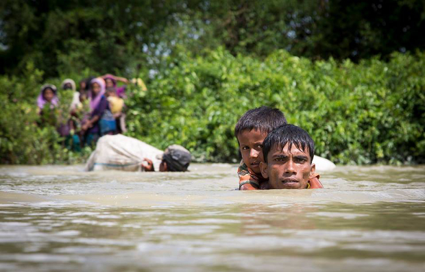শিশুকে কাঁধে নিয়ে নাফ নদী সাঁতরে উখিয়ার আঞ্জুমানপাড়ায় ঢুকছেন এক রোহিঙ্গা। ১৩ অক্টোবর ২০১৭।