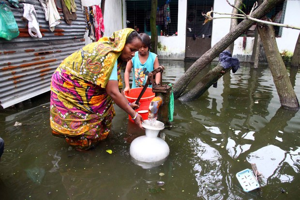 বন্যার পানি ঢুকে পড়েছে রাজধানী ঢাকার আশে পাশেও। ডুবে যাওয়া মাতুয়াইলের মেডিকেল রোড এলাকায় খাবার পানি সংগ্রহ করছেন এক নারী। 