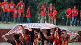 ঢাকায় বিশ্ব আদিবাসী দিবসের শোভাযাত্রা চলাকালে বৃষ্টি থেকে বাঁচতে একটি ব্যানার দিয়ে মাথার ছাদ তৈরি করে নিয়েছেন আদিবাসী নারীরা।