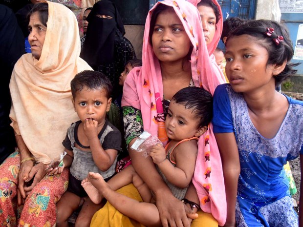 বৃষ্টির কারণে খোলা জায়গায় আশ্রয় নেওয়া এক রোহিঙ্গা পরিবার লেদা ক্যাম্পের ভেতরে একটি দোকানের পাশে বসে আছে। বৃষ্টির কারণে খোলা জায়গায় আশ্রয় নেওয়া এক রোহিঙ্গা পরিবার লেদা ক্যাম্পের ভেতরে একটি দোকানের পাশে বসে আছে।