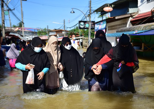 People wade through floodwaters after heavy rains in Sungai Kolok, a district in the Muslim-majority province of Narathiwat in southern Thailand, Dec. 20, 2021.