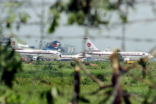 Planes belonging to Biman Bangladesh Airlines are visible through storm-damaged trees at Zia International Airport in Dhaka, April 23, 2003. 