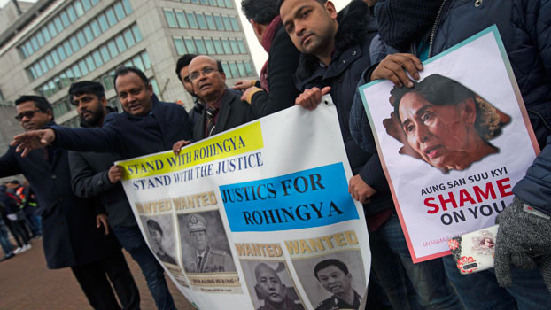 Demonstrators hold signs outside the International Court of Justice in The Hague, where Myanmar leader Aung San Suu Kyi attended the first day of three days of hearings, Dec. 10, 2019. [AP]