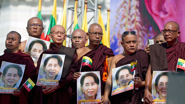 Buddhist monks hold portraits of Myanmar leader Aung San Suu Kyi while standing on a stage to pray during a rally in front of City Hall in Yangon, Dec. 10, 2019. [AP]