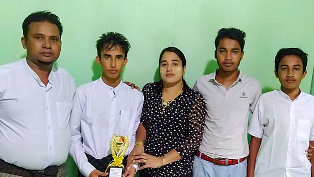 Rohingya student Muhammad Ayaz (second from left) holds a trophy he received in recognition of his scholastic achievements as he stands beside his parents and brothers at their home in Buthidaung town, in Myanmar’s Rakhine state, in an undated photo. [Photo courtesy of Muhammad Ayaz's family]