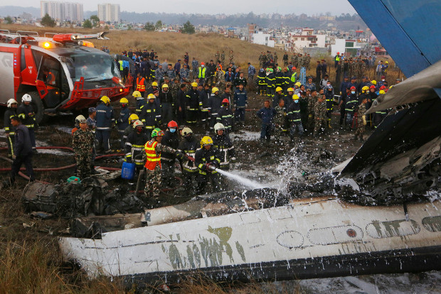 Nepalese firemen spray water on the debris of crashed US-Bangla Flight 211, March 12, 2018. [AP]