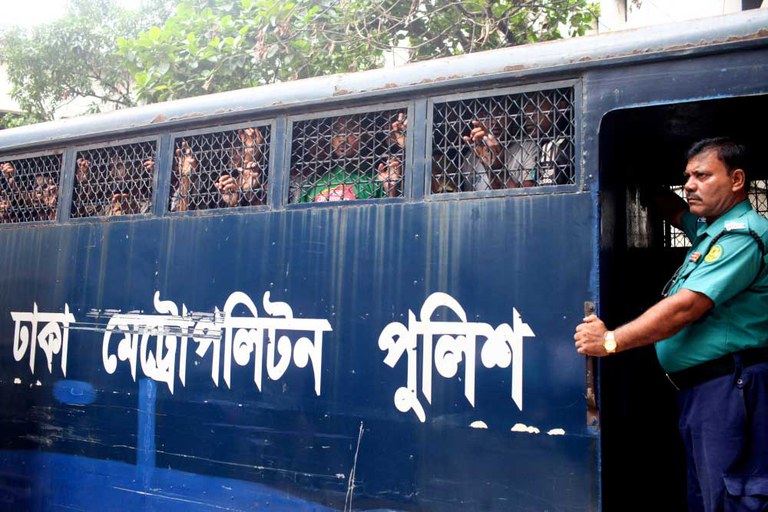 An officer stands at the front of a police van transporting arrested people to a Dhaka court, July 23, 2024. [Abu Sufian Jewel/AFP]