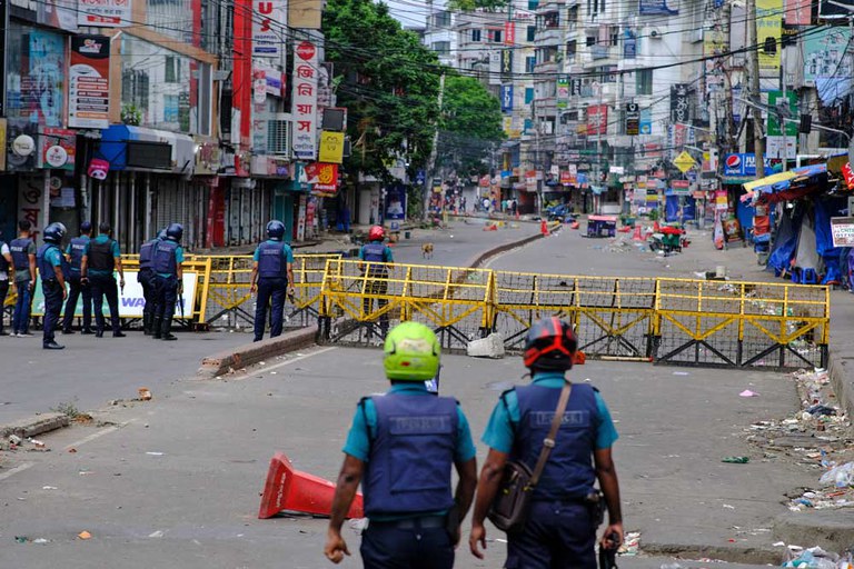 Bangladesh police stand behind a barricade on a Dhaka street during the curfew tied to anti-quota protests, July 21, 2024. [Mahmud Hossain Opu/AP]
