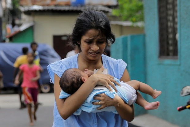 A Sri Lankan woman living near St. Anthony’s Shrine church runs for safety with her infant after police found explosive devices in a parked vehicle in Colombo, Sri Lanka, April 22, 2019, a day after nearly 300 people were killed in Easter Sunday bombings that targeted churches and luxury hotels in the country. [AP]