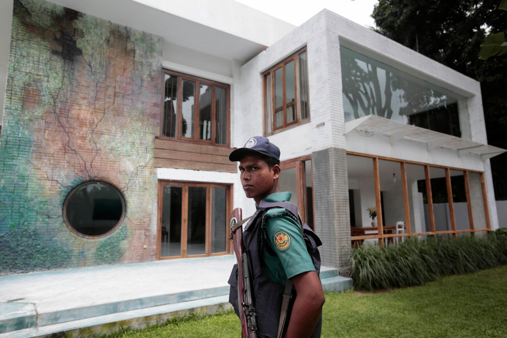 A Bangladeshi policeman stands guard in front of the building that once housed the Holey Artisan Bakery, on the first anniversary of a deadly hostage crisis at the upscale restaurant in Dhaka, July 1, 2017. [AP]