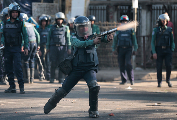 A Bangladeshi police officer fires tear gas at demonstrators protesting against plans to build a coal-fired power plant, in Dhaka, Jan. 26, 2017. (AP)