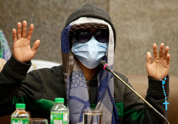 An eyewitness concealing his identity gestures during a Philippine senate investigation in Manila into the death of Kian Loyd Delos Santos, a 17-year-old student who was killed in an alleged drug crackdown, Sept. 5, 2017. (AP)