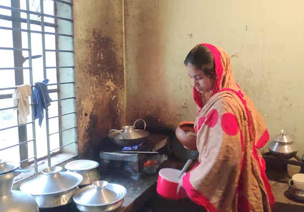 Shipa Akhter cooks in a kitchen that she and her husband share with another family at their home in Dakshinkhan, Bangladesh, July 20, 2019. [Jesmin Papri/BenarNews]