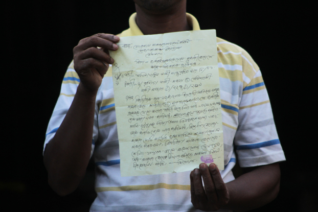 Mohammad Rashid, an official with the development committee at the Leda refugee camp in Teknaf, Bangladesh, holds up a letter from Sakhina Khatun, a mother of two missing Rohingya girls seeking the committee’s help in finding them, Aug. 26, 2018. (Sharif Khiam/BenarNews)
