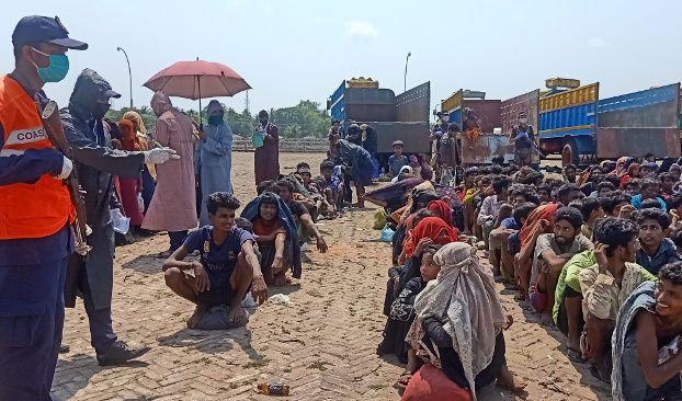 A Bangladesh Coast Guard member lines up rescued Rohingya outside the Bangladesh-Myanmar transit center at Teknaf, Cox’s Bazar, April 16, 2020. [Abdur Rahman/BenarNews]