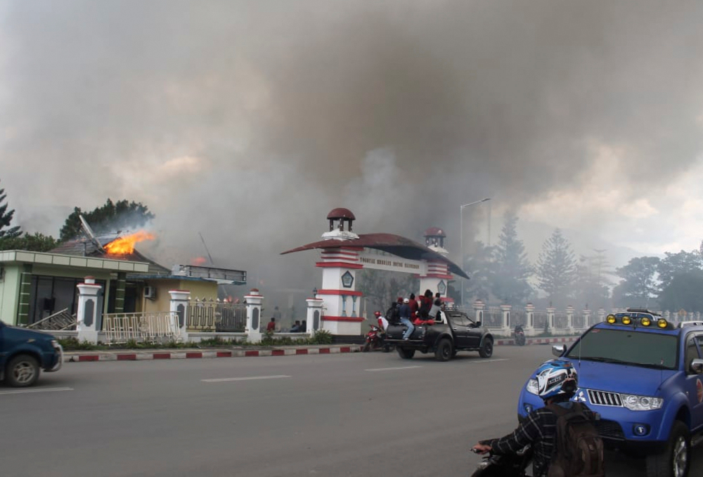 Residents drive past a burning government building during a protest that turned violent in Wamena, Papua province, Indonesia, Sept. 23, 2019. [AP]
