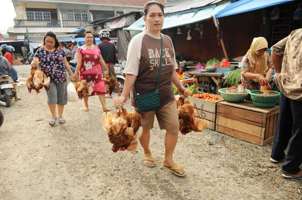 Palu residents carry chicken they bought from a market which reopened days after a powerful quake and tsunami battered Indonesia’s Central Sulawesi province, Oct.  4, 2018. [Keisyah Aprilia/BenarNews]