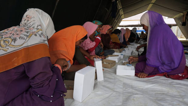 A group of Rohingya eat meals provided by the local government in Lhokseumawe, Aceh province, a day after their arrival in Indonesia, Sept. 8, 2020. [Muzakir Nurdin/BenarNews]