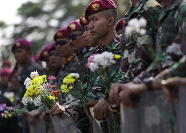 Indonesian marines hold flowers handed out by student protesters during a rally outside the parliament in Jakarta, Oct. 1, 2019. 