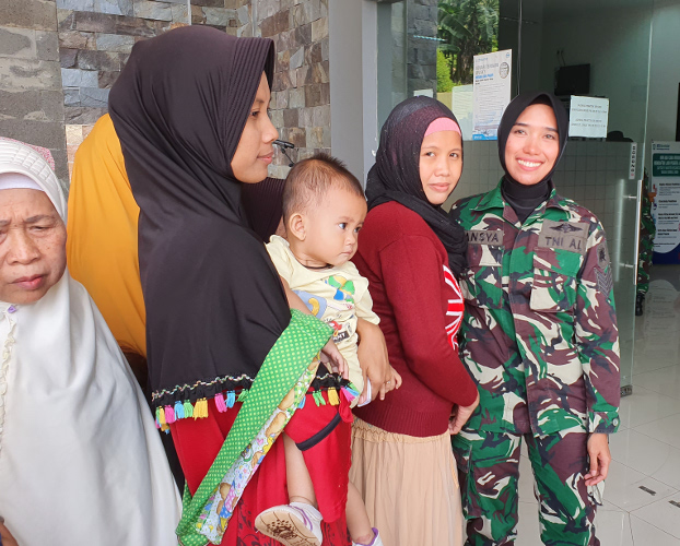 Tansya Susan, an Indonesian Navy sergeant, greets women and children waiting for medical care at the clinic outside of Jakarta, Aug. 6, 2019. (Ahmad Syamsudin/BenarNews)