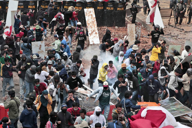 Student protesters react as police fire tear gas during a rally against a controversial law on job creation in Jakarta, Oct. 8, 2020. [AP]