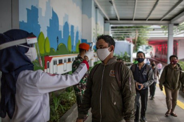 An official checks the body temperature of passengers at Jakarta’s Sudirman Station, as the Indonesian capital loosened the two-month partial lockdown caused by the coronavirus pandemic, June 5, 2020. [Afriadi Hikmal/BenarNews]