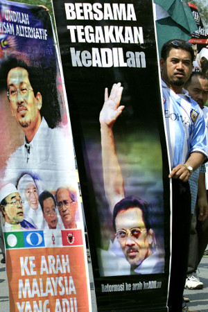 A supporter of Anwar Ibrahim holds a banner depicting Anwar’s black eye during a peaceful demonstration to mark the opposition leader’s 54th birthday, in Sungai Buloh, Malaysia, Aug. 12, 2001. [AFP]