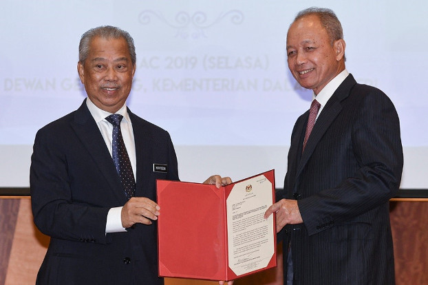 Home Minister Muhyiddin Yassin (left) presents a Royal Commission of Inquiry appointment letter to former Chief Justice Arifin Zakaria in Putrajaya, Malaysia. March 5, 2019. [S. Mahfuz/BenarNews]