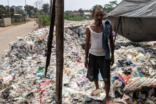 A man stands on tons of imported plastic trash at a dumpsite in Bekasi, a city in West Java, Indonesia, May 16, 2018. [Ahmad Syamsudin/BenarNews]