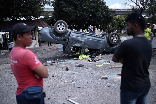 Authorities and residents look at a vehicle damaged during violence outside the Sri Maha Mariamman temple in Subang Jaya, Nov. 26, 2018. [S.Mahfuz/BenarNews]