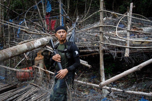 A member of the Malaysian General Operation Force stands guard at an abandoned human-trafficking camp found outside Wang Kelian in Malaysia, May 26, 2015. [AP]