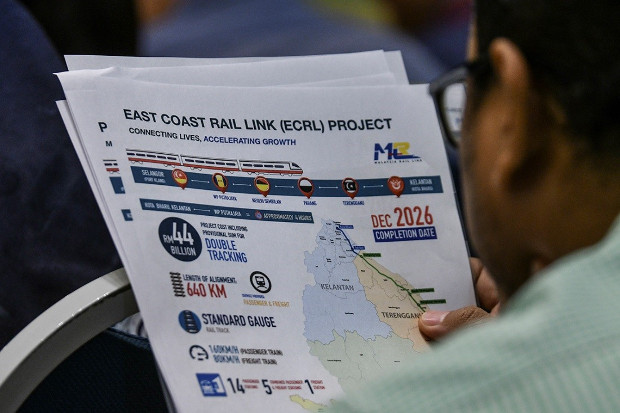 A journalist reads a handout on the East Coast Rail Link project distributed at a press conference in Putrajaya, Malaysia. April 15, 2019. [S. Mahfuz/BenarNews]