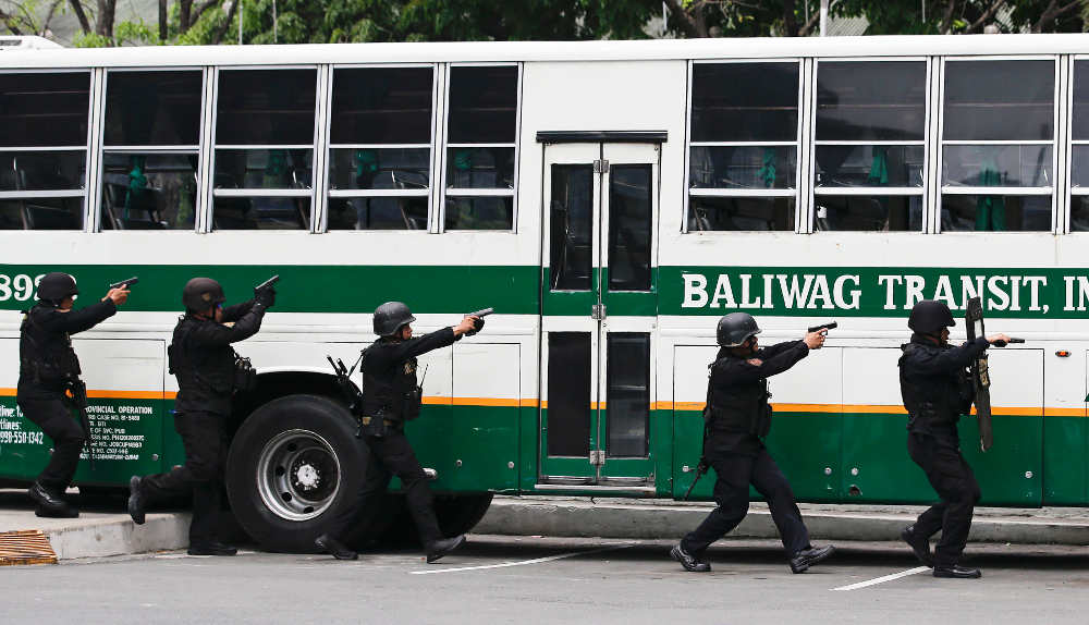 Police aim their pistols toward a bus during a hostage-taking scenario as part of anti-terrorism drills conducted by police and military units in Manila, April 12, 2018. 