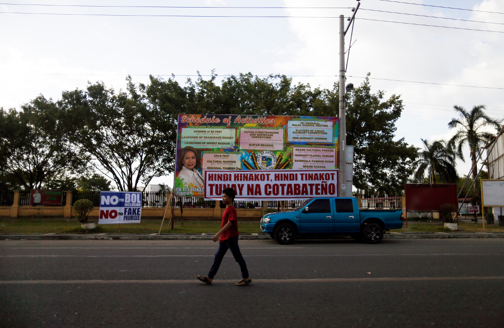 A resident crosses a street in Cotabato City, southern Philippines, ahead of a Jan. 21 plebiscite on ratifying the Bangsamoro Organic Law (BOL), which would give former Muslim rebels full control over an autonomous homeland in the region, Jan. 13, 2019. [Jeoffrey Maitem/BenarNews] 