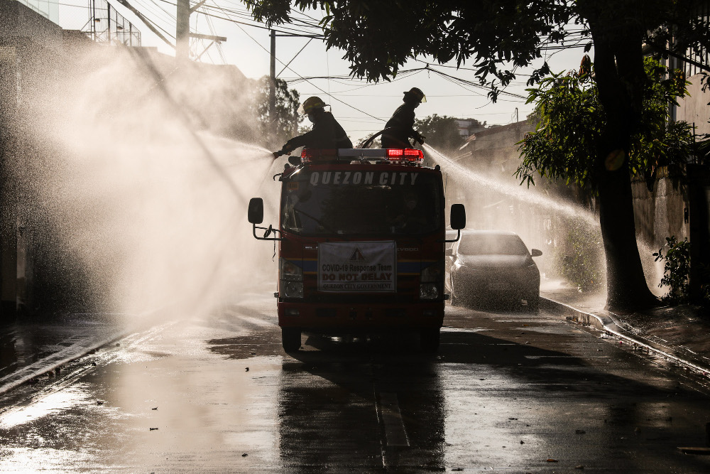 Government emergency workers spray disinfectant solution on the street in suburban Quezon City, north of Manila, March 28, 2020. [Basilio Sepe/BenarNews]