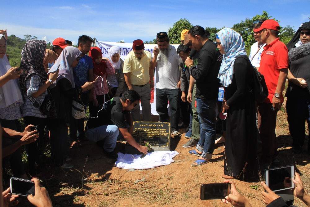 Residents of Marawi unveil a memorial plaque at the site of a mass grave holding the bodies of 281 unidentified people, who died during a five-month takeover of the city by militants and a battle with government forces that ensued, May 23, 2019. [Richel V. Umel/BenarNews]