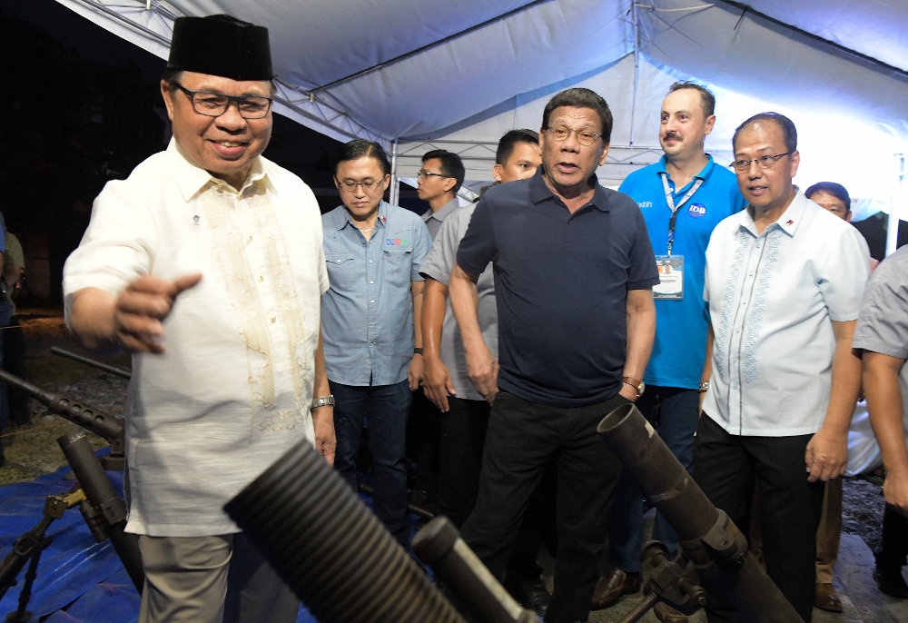 President Rodrigo Duterte (center) joins Moro Islamic Liberation Front leader Ebrahim Murad (left) in inspecting decommissioned firearms in Sultan Kudarat town, southern Philippines, Sept. 7, 2019. (Photo: Froilan Gallardo/BenarNews)