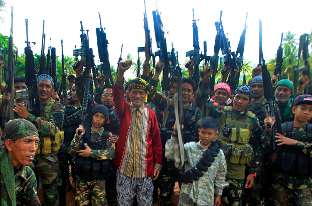 Two boys flank MNLF leader Nur Misuari (center), as they and other guerrillas raise their weapons at a remote camp in Jolo, southern Philippines, May 29, 2016. [Mark Navales/BenarNews]