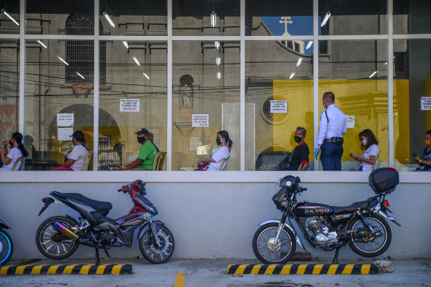 A security guard wearing a face mask monitors social distancing protocols of people waiting to enter a department store in Dagupan City, northern Philippines, May 18, 2020. [Jojo Rinoza/BenarNews]