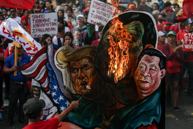 A Philippine activist burns effigies of President Rodrigo Duterte, U.S. President Donald Trump and Chinese President Xi Jinping during a rally in Manila, Nov. 30, 2019. [Basilio Sepe/BenarNews]
