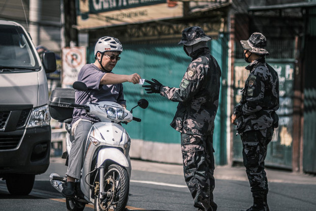 Philippine police ask a man to present his pass at a checkpoint in Manila, March 24, 2020. [Luis Liwanag/BenarNews] 