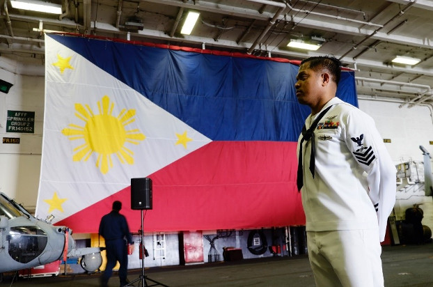 U.S. Navy Petty Officer Fernan Testa stands near a Philippine flag aboard the USS Ronald Reagan after the aircraft carrier dropped anchor in Manila Bay, Aug. 7, 2019. [Jason Gutierrez/BenarNews]