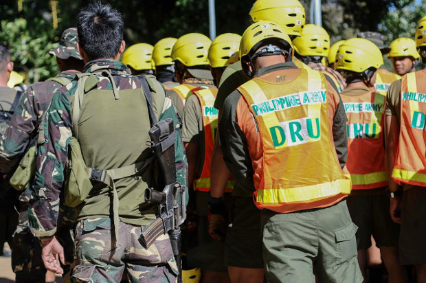 Philippine rescuers and soldiers take part in a morning prayer before starting retrieval operations in Ucab, Itogon, Sept. 18, 2018. 