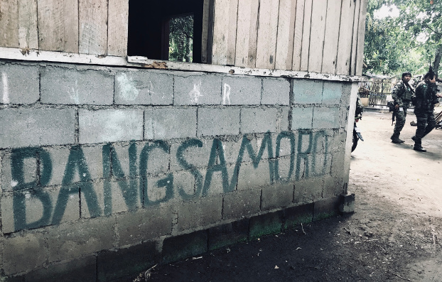 Moro Islamic Liberation Front fighters walk past a sign declaring the region Bangsamoro, June 22, 2019. (Jason Gutierrez/BenarNews)