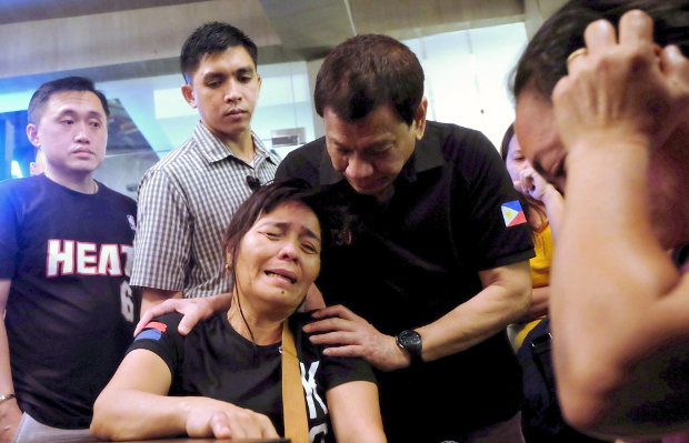 Philippine President Rodrigo Duterte comforts a relative of one of the victims of a fire that engulfed a shopping mall in Davao City, Dec. 23, 2017. 